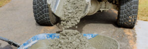Mixer truck pours concrete into wheelbarrow at construction site