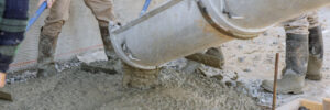 It is concrete mixing truck pouring concrete around new house that will be used for pavement