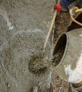 Workers pour concrete solution at a construction site .