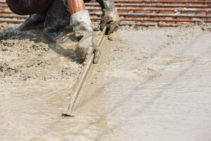 Close up worker hand using float to level surface of concrete
