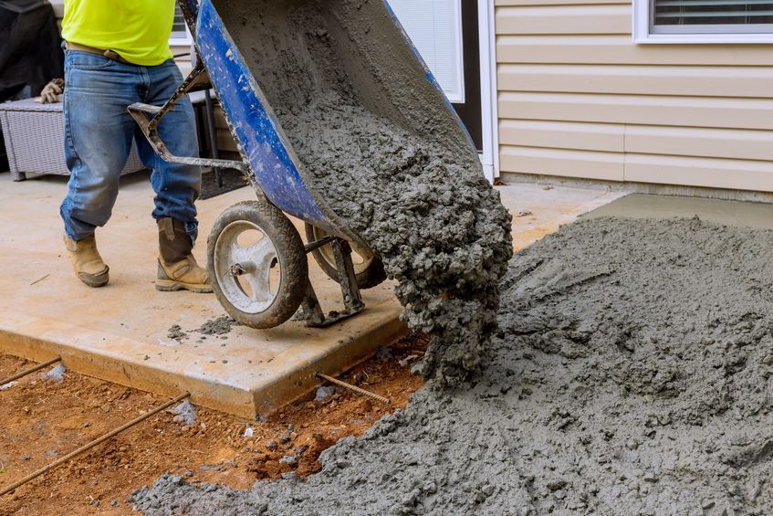 man pouring concrete from wheelbarrow
